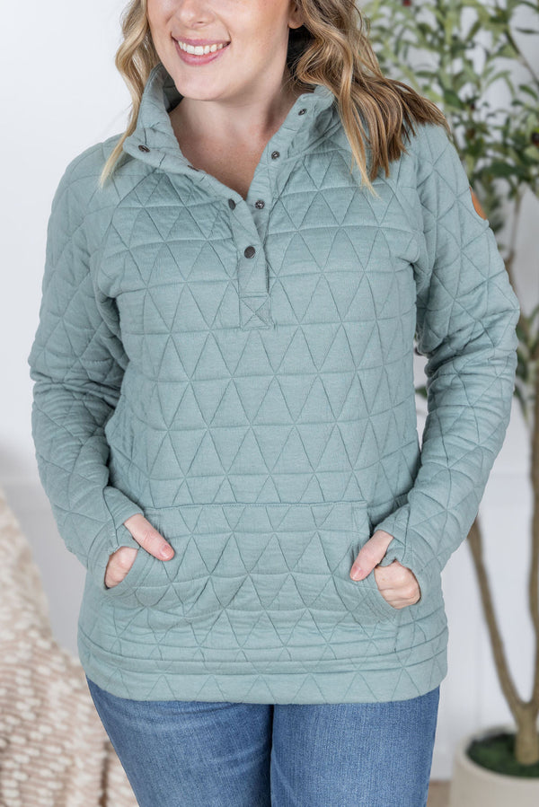 Woman wearing a light blue quilted pullover with a neutral background