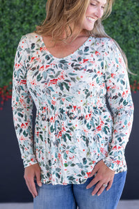 Woman wearing a floral long-sleeve top with a blurred green and blue background