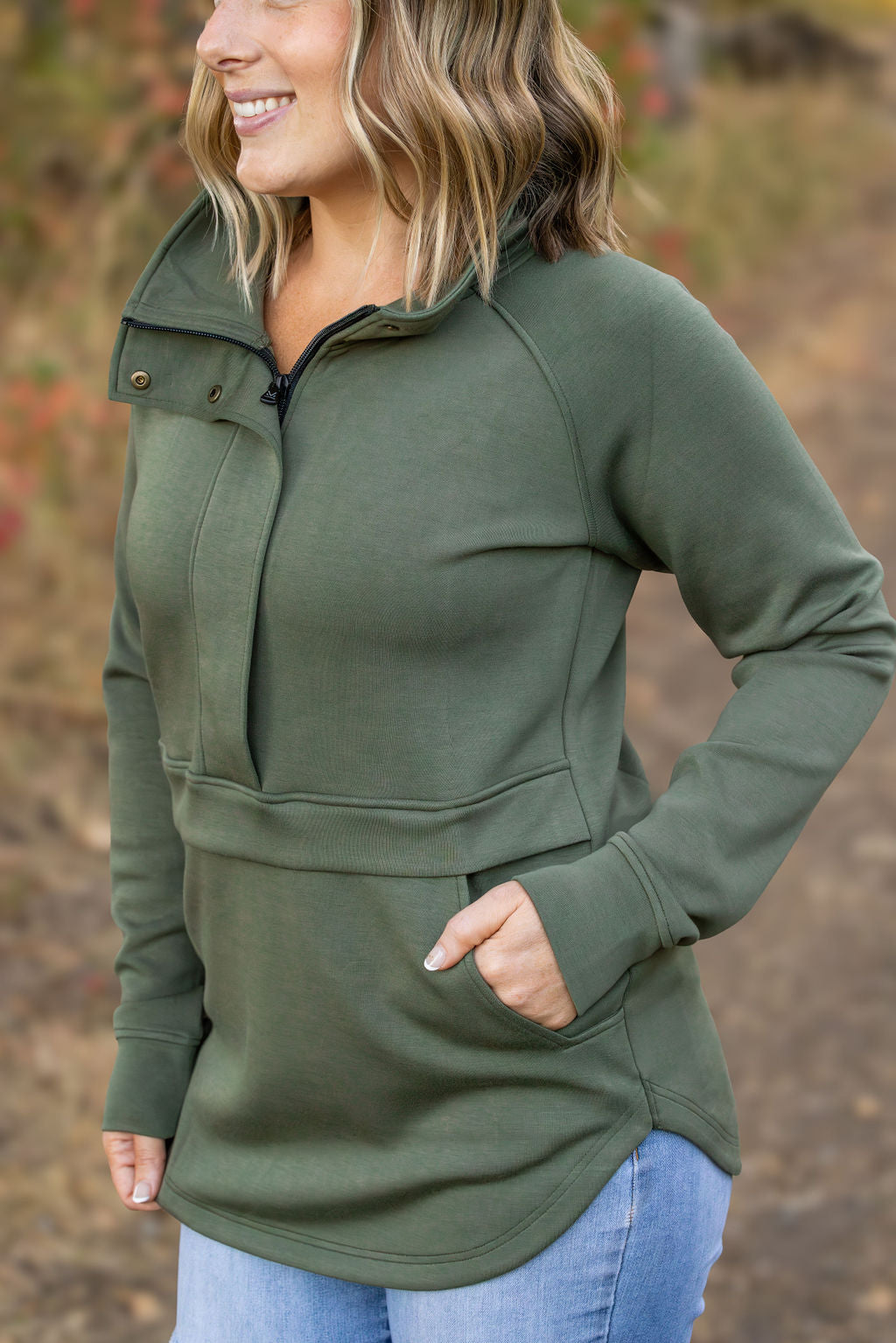 Woman wearing a green pullover with a blurred natural background