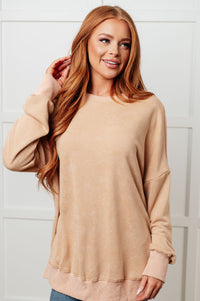 Woman wearing a beige sweater against a white background