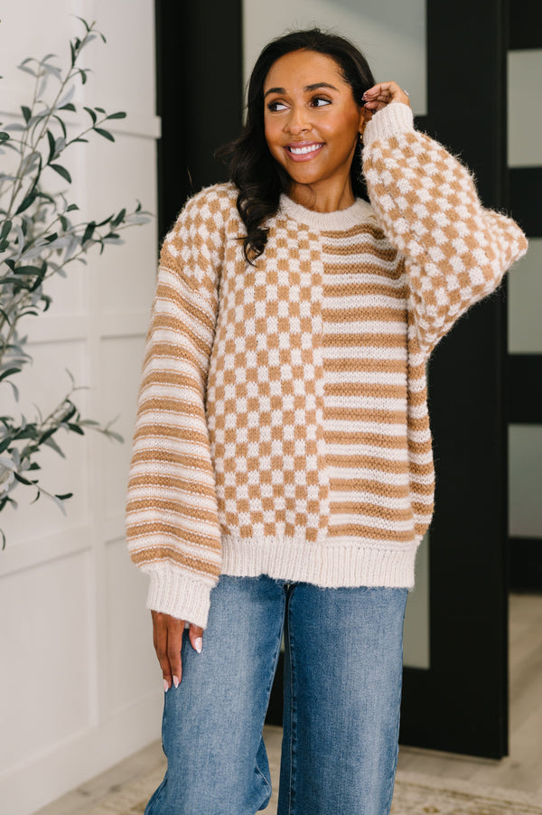 Woman wearing a checkered sweater and jeans, standing indoors.