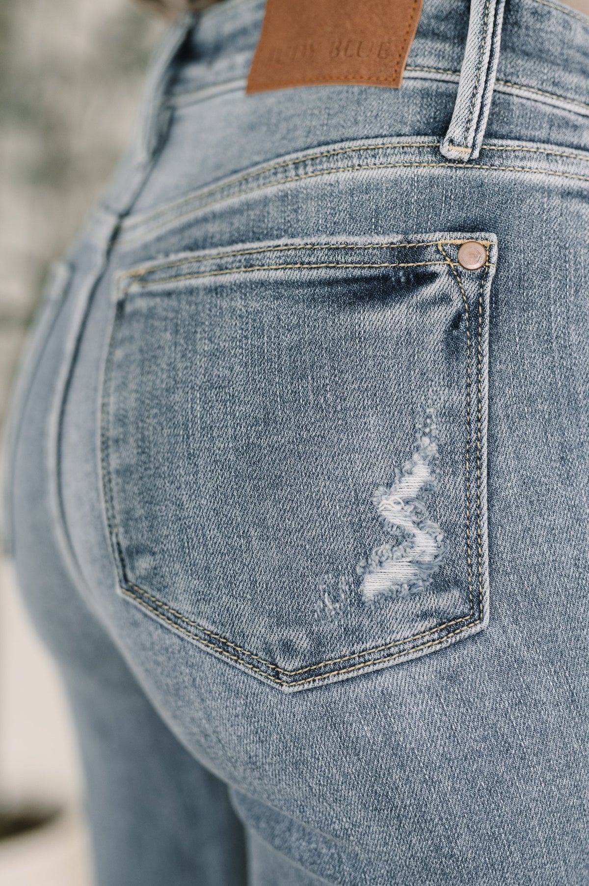 Close-up of a blue denim pocket with a brand logo, blurred background