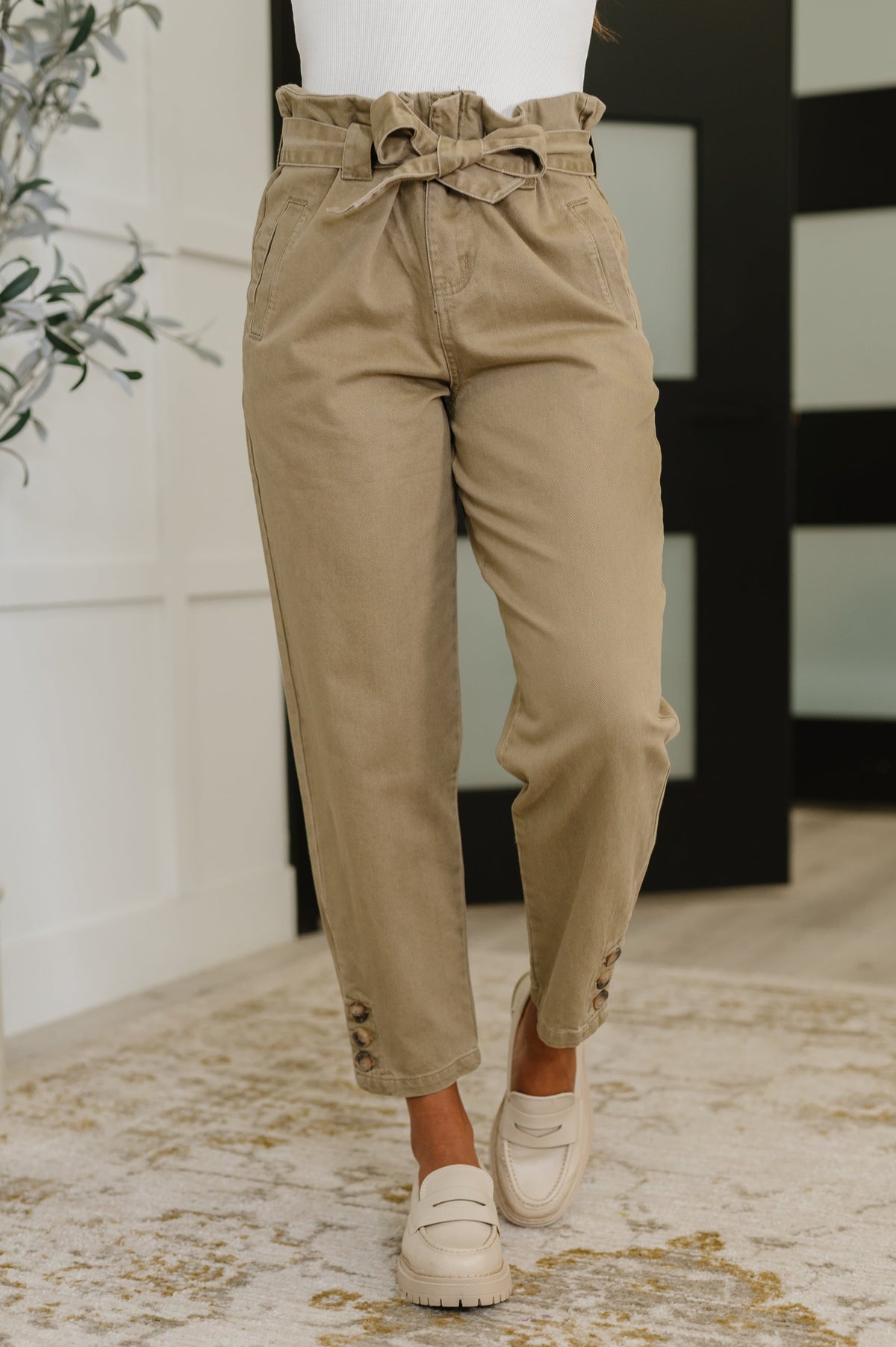 Person wearing beige paperbag waist pants with a blurred background