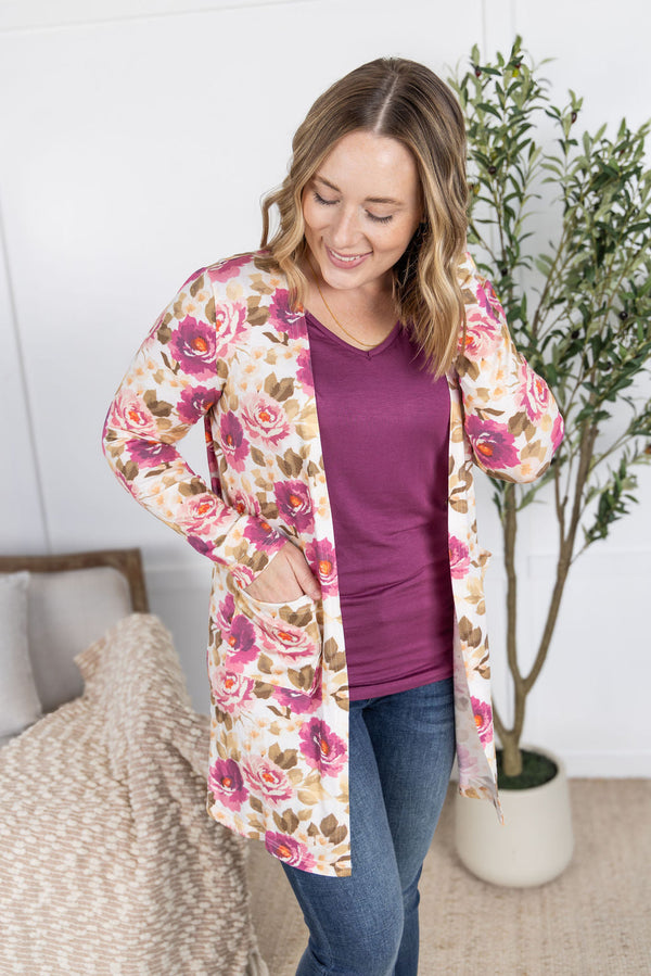 Woman wearing a floral cardigan over a purple shirt in a home setting