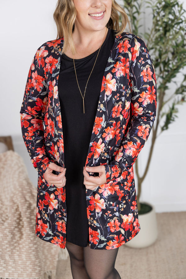 Woman wearing a floral cardiagn over a black dress in an indoor setting.