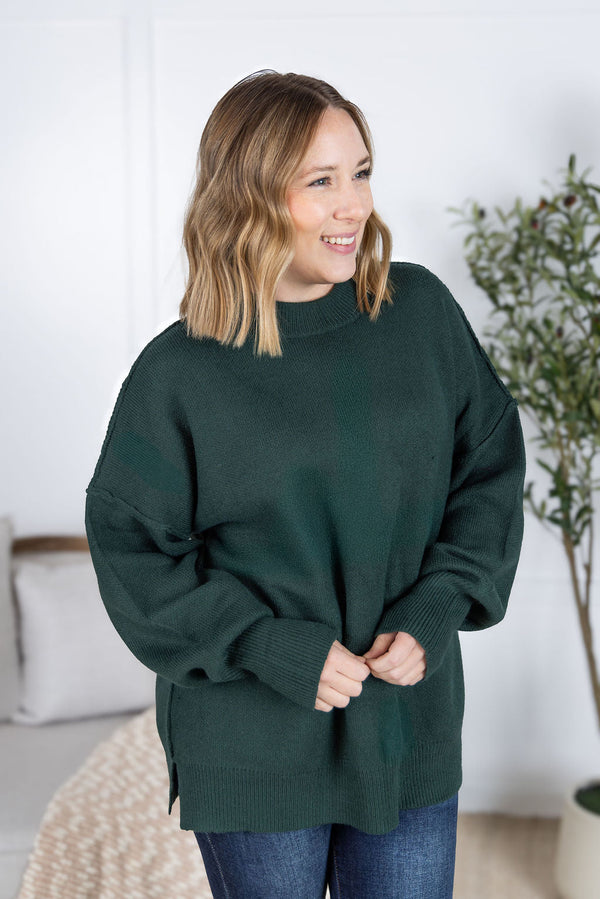 Woman wearing a dark green sweater in a home setting