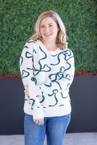 woman wearing a white sweater with green ribbon pattern 