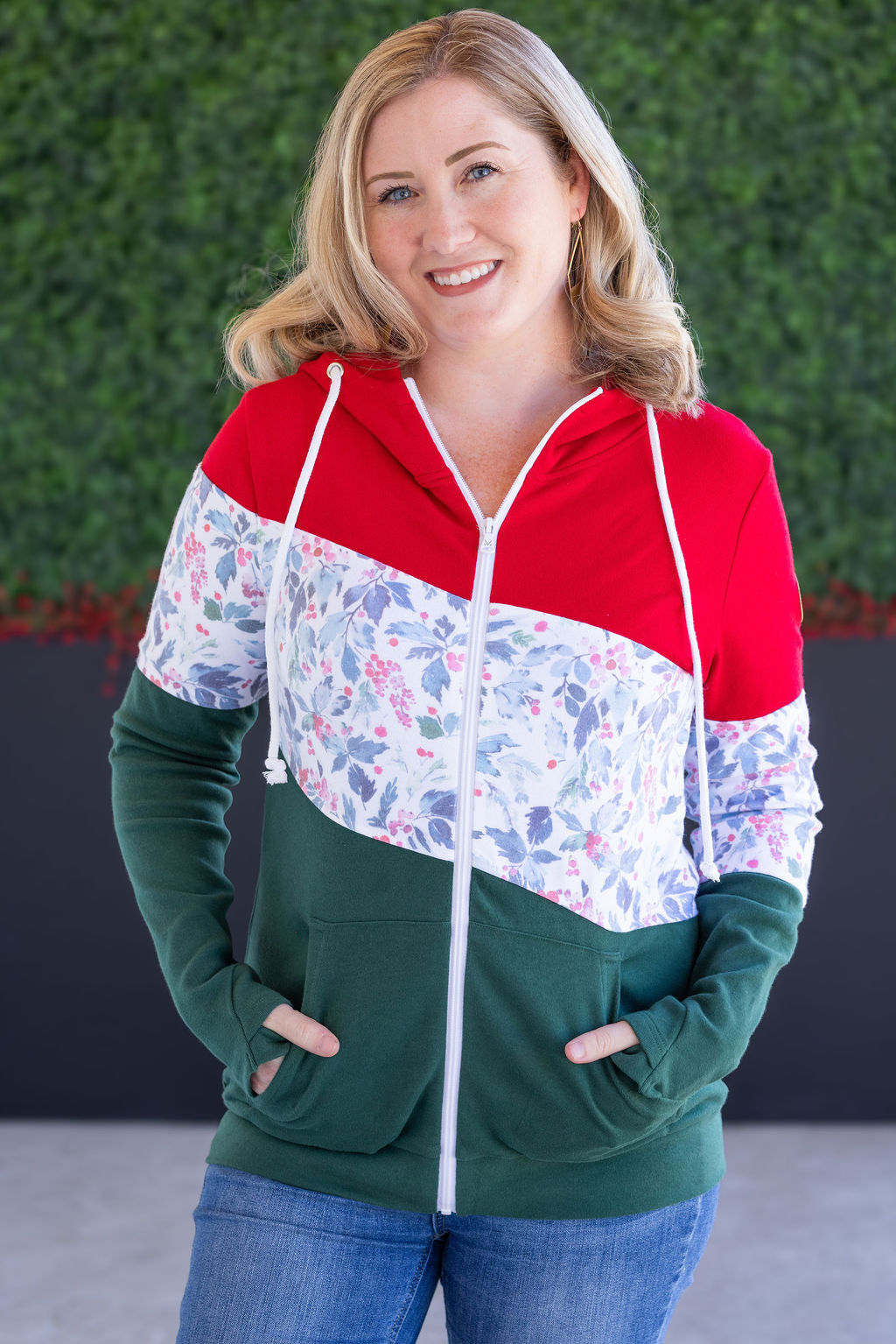 Woman wearing a colorful hoodie with a floral pattern on a green and red background