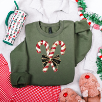 Green sweatshirt with candy cane design on a festive background with tinsel and mug.