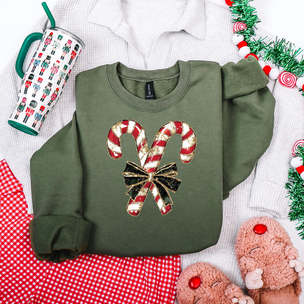 Green sweatshirt with candy cane design on a festive background with tinsel and mug.