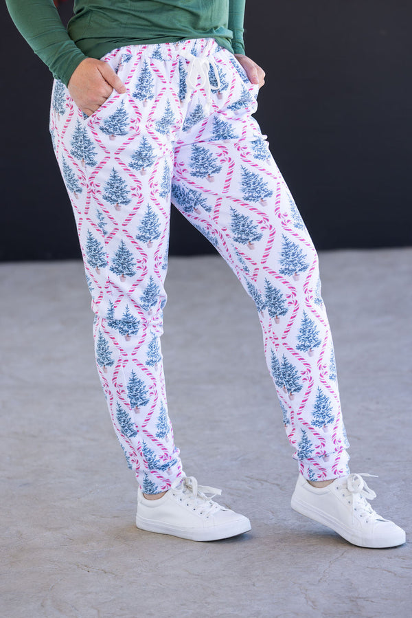 Person wearing white jogger pants with blue and pink tree pattern on a gray floor.