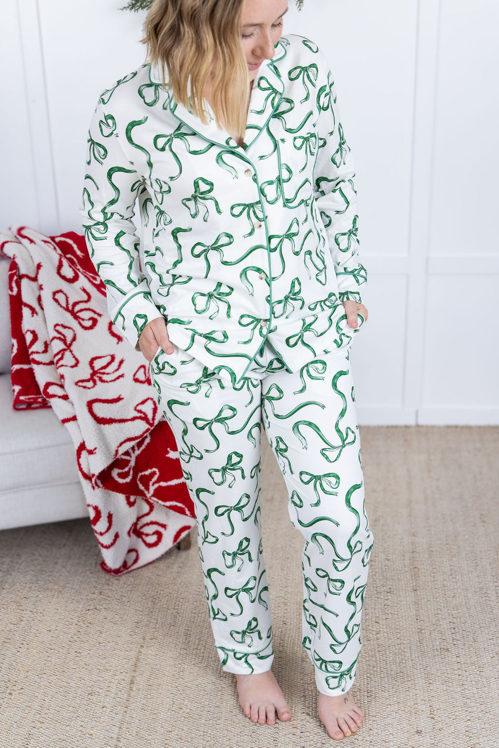 Person wearing a green and white patterned onesie standing in a room with a red blanket.