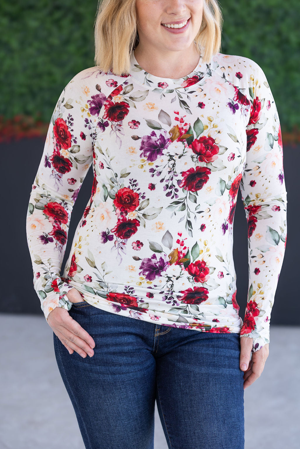 Woman wearing a floral long-sleeve top with a blurred green background