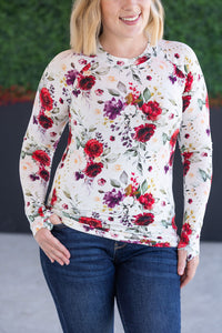 Woman wearing a floral long-sleeve top with a blurred green background