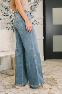 Person wearing blue wide-leg jeans in a room with decorative elements.