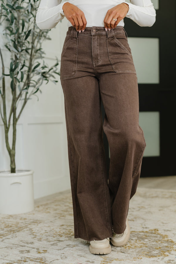 Person wearing brown wide-leg pants and a white shirt indoors.