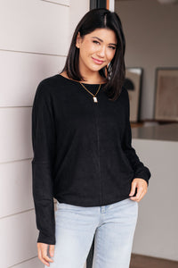 model wearing a black top in front of a white wall 