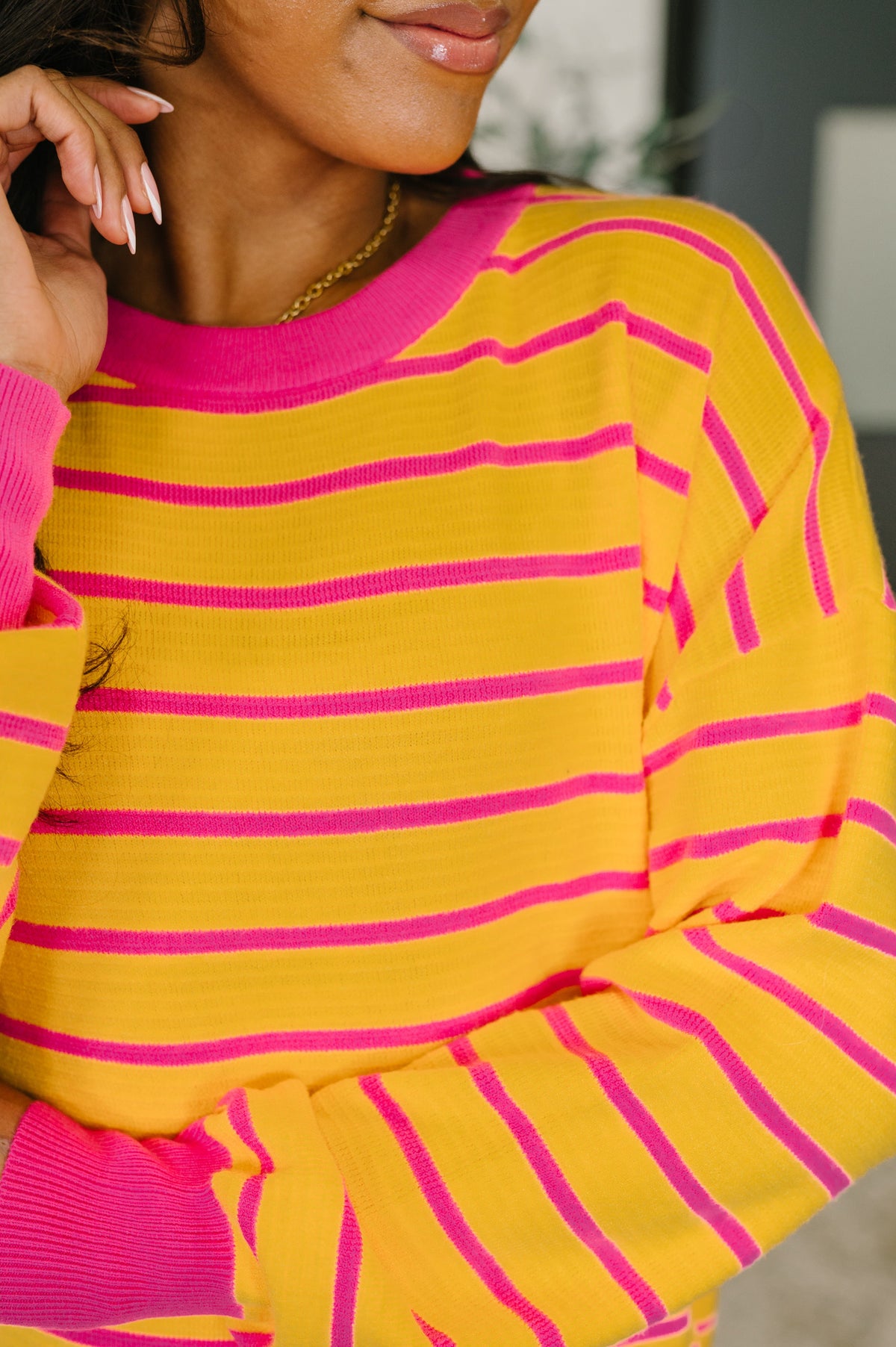 Person wearing a yellow and pink striped outfit with a blurred background