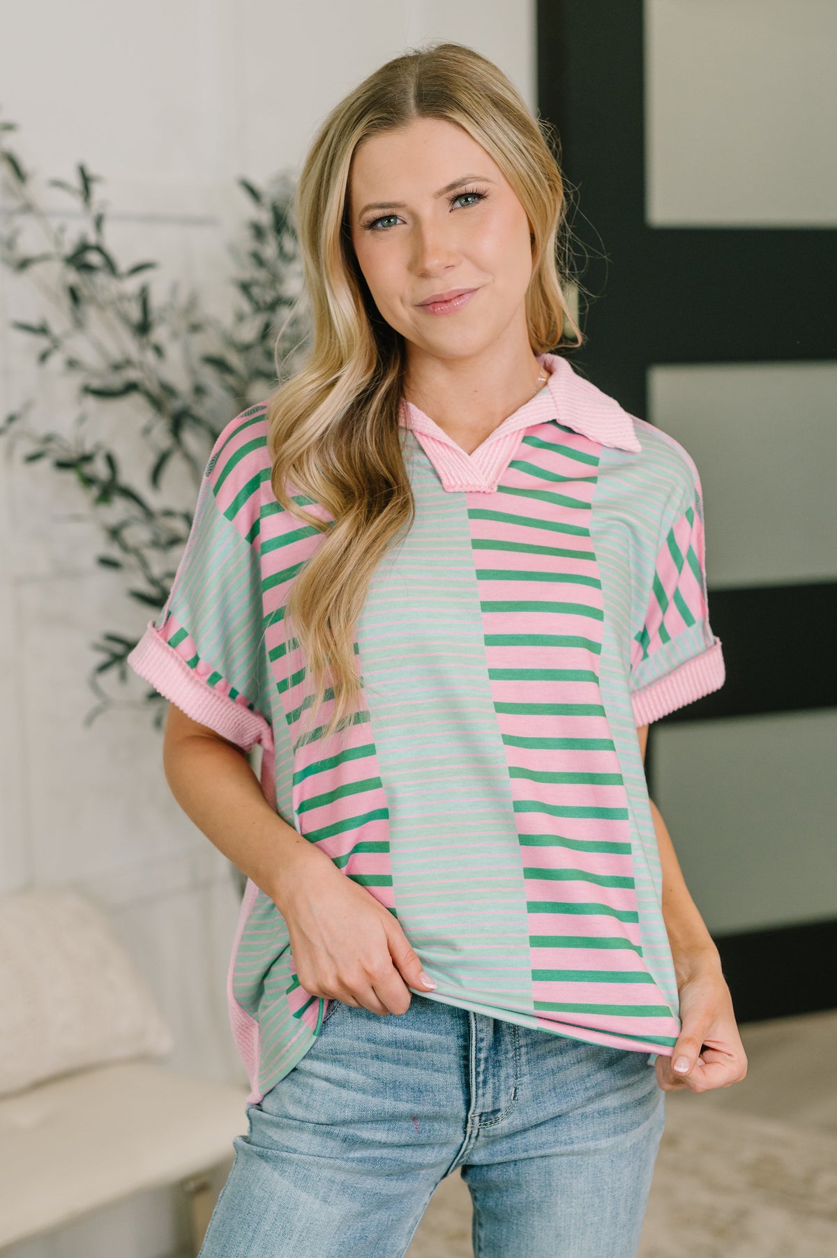 Woman wearing a striped shirt with pink and green horizontal stripes indoors.