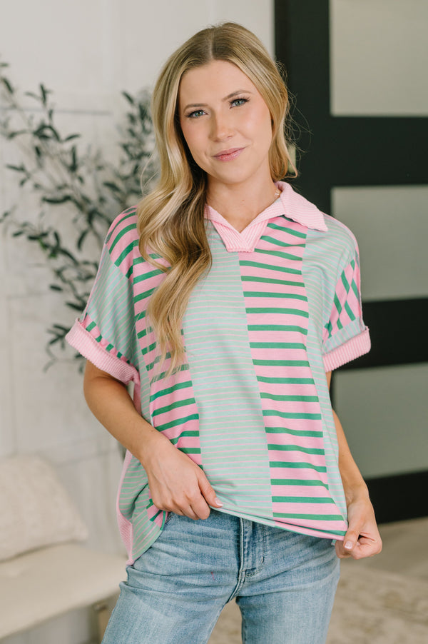 Woman wearing a striped shirt with pink and green horizontal stripes indoors.