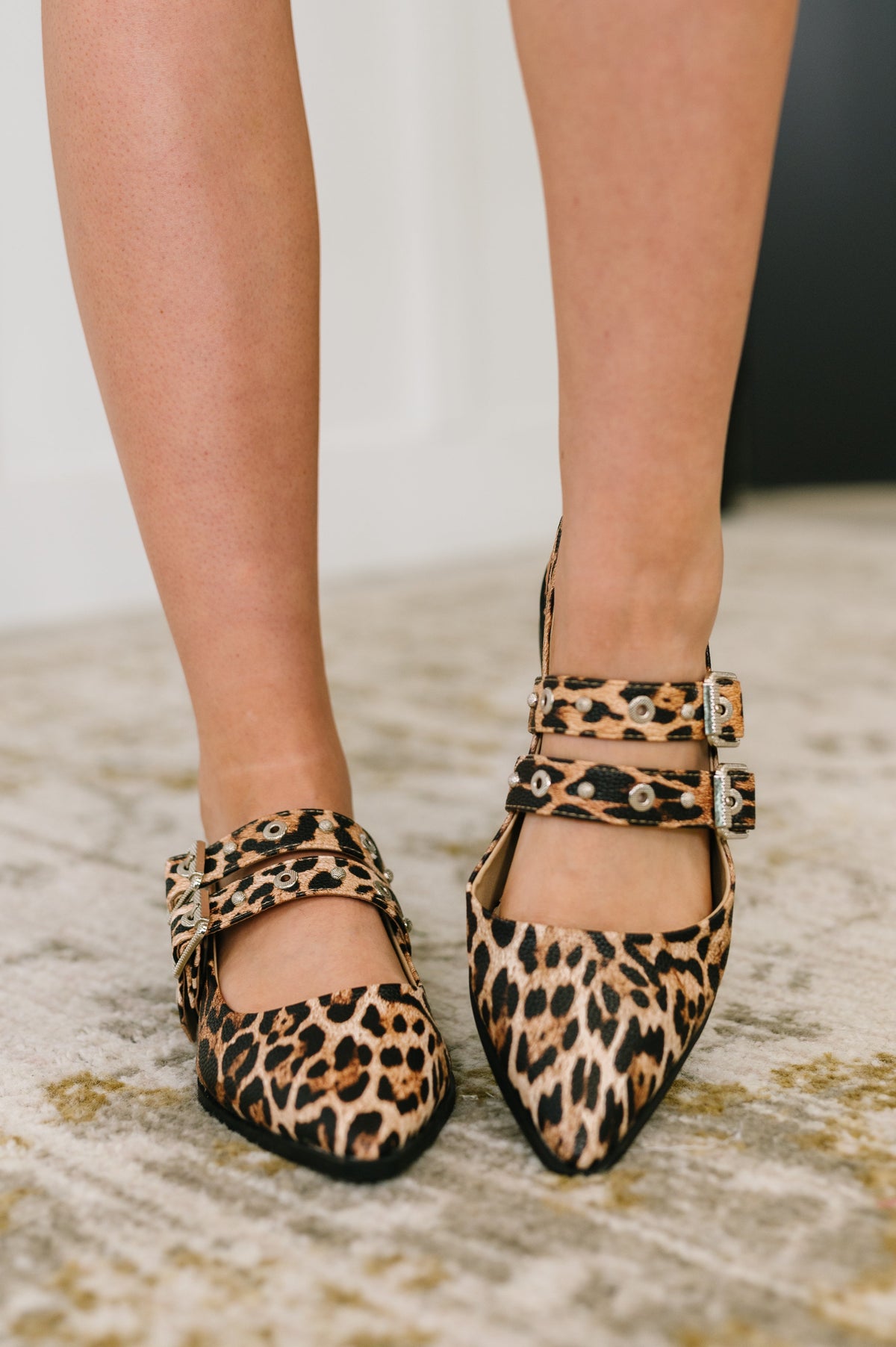 Leopard print shoes worn by a person on a neutral background