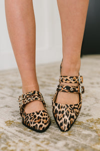 Leopard print shoes worn by a person on a neutral background