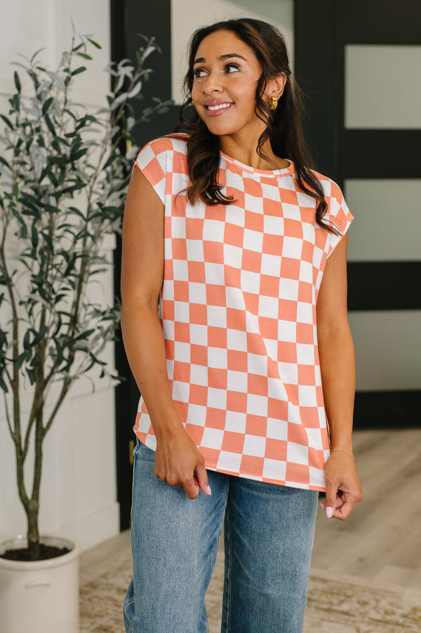 Woman wearing a checkered shirt and jeans indoors with a plant in the background