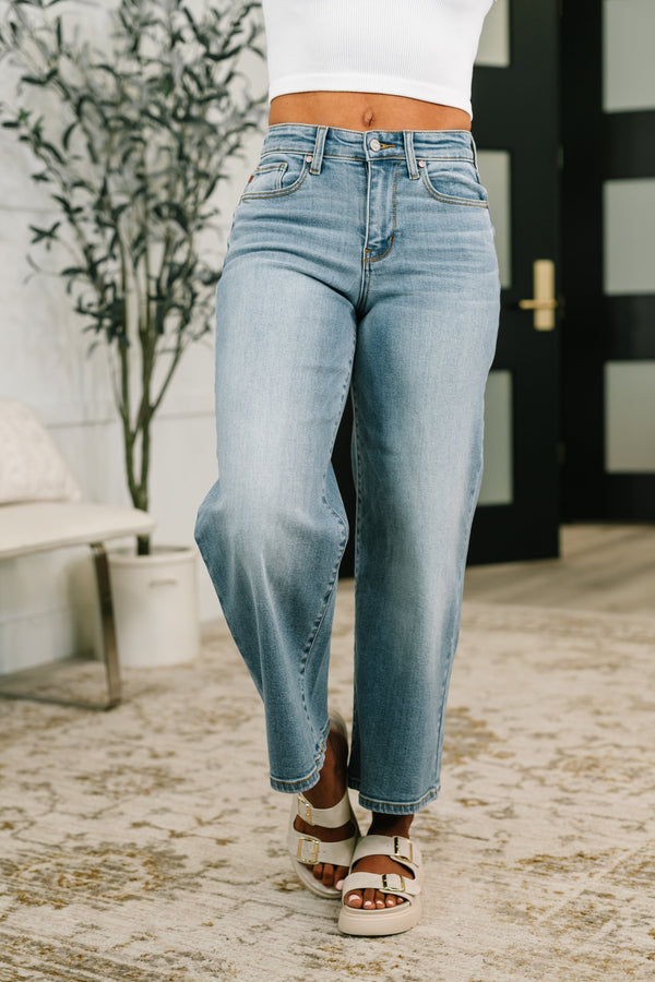 Person wearing light blue jeans and white sandals in an outdoor setting.