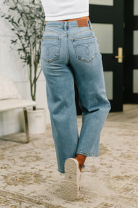 Person wearing light blue jeans walking on a textured floor.
