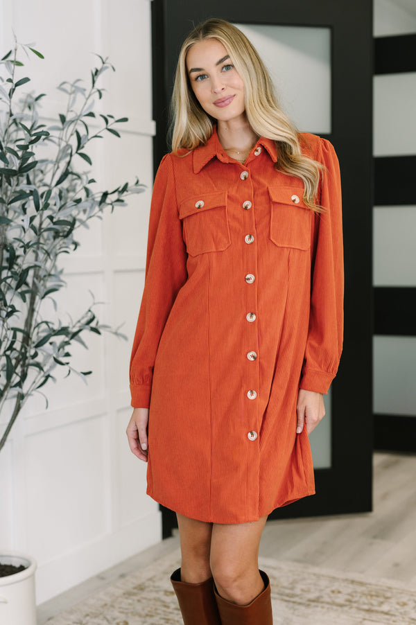 Woman wearing an orange dress with a plant and door in the background