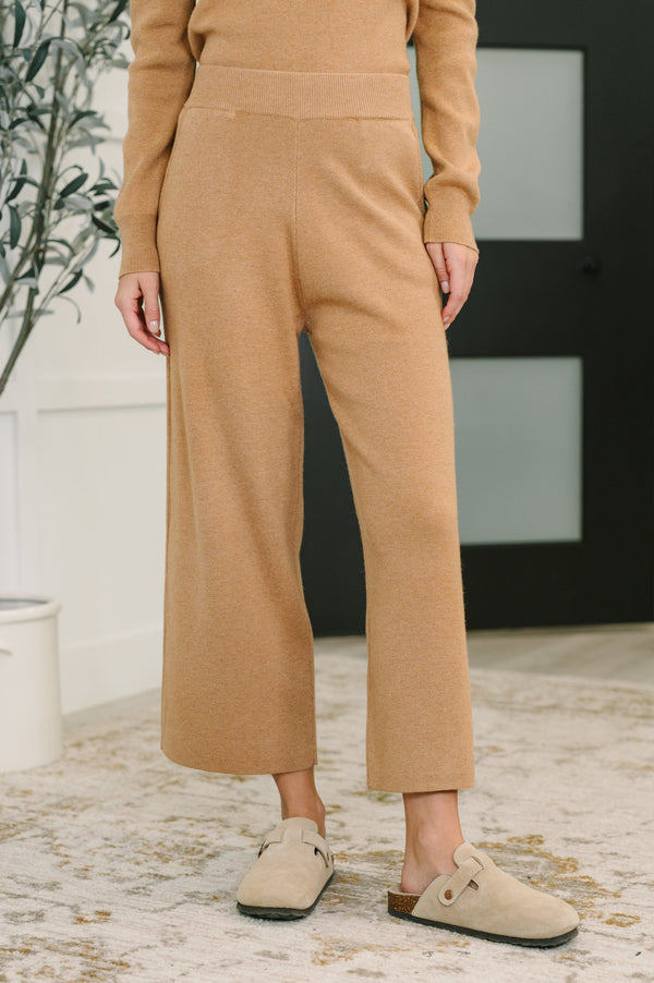 Person wearing a beige outfit with wide-leg pants indoors.