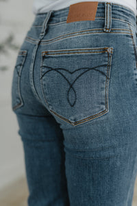 Close-up of blue jeans with a heart design on the pocket and a brand tag.