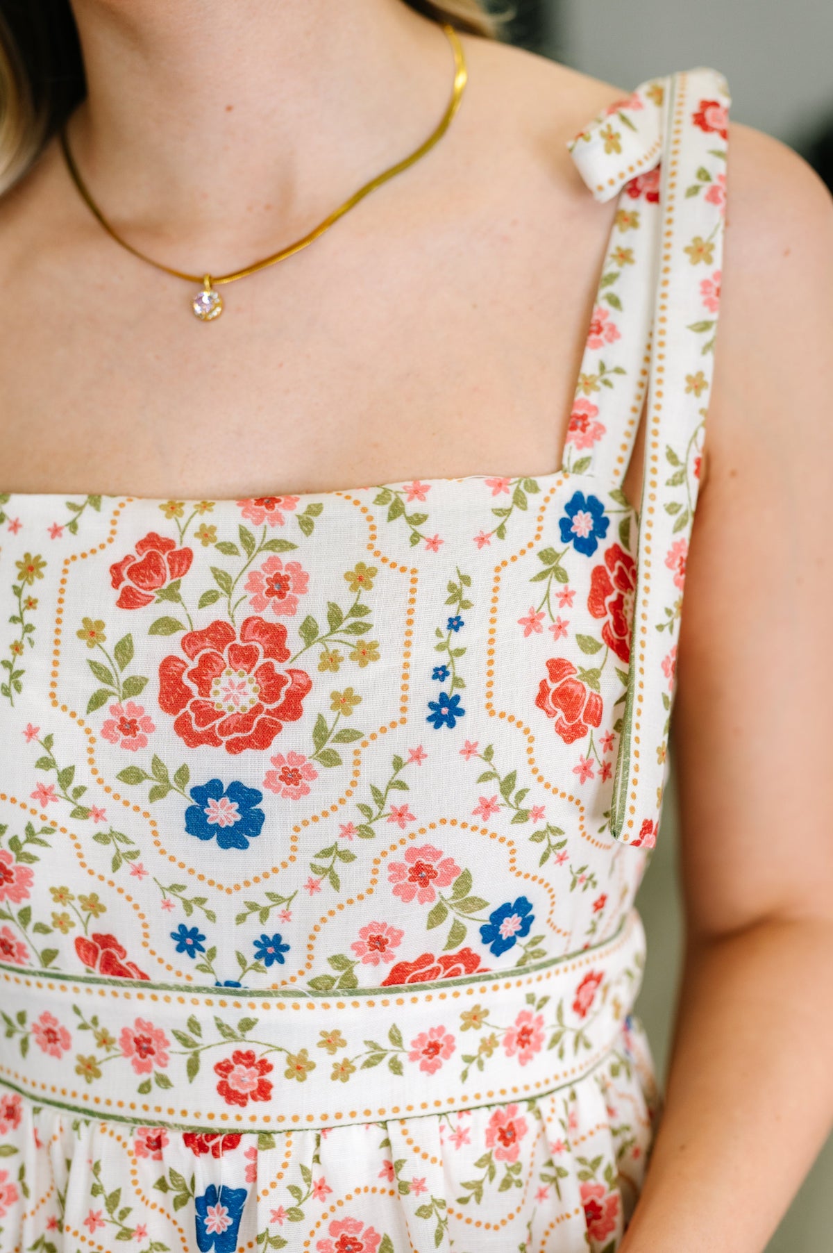 Floral dress with a gold necklace on a blurred background
