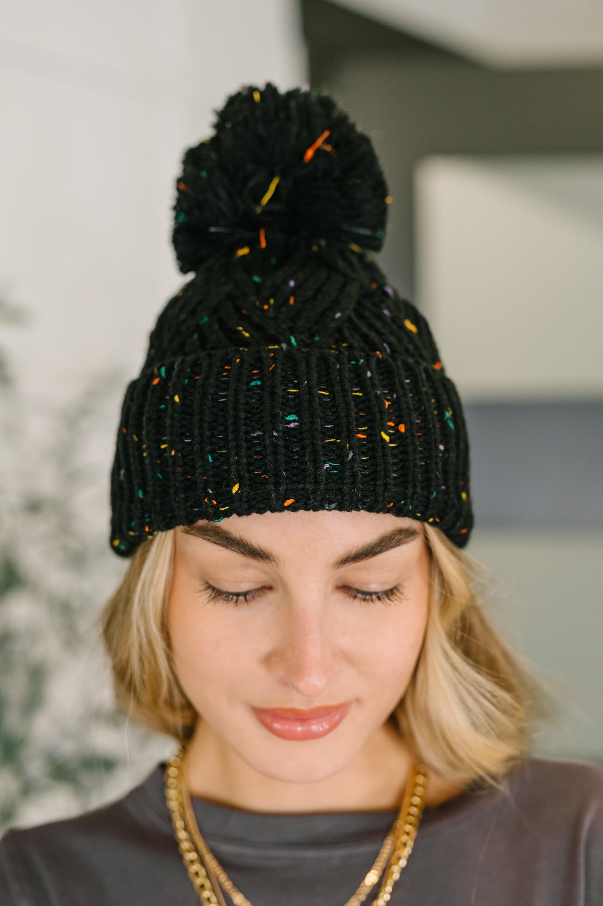 Person wearing a black knit beanie with colorful accents indoors