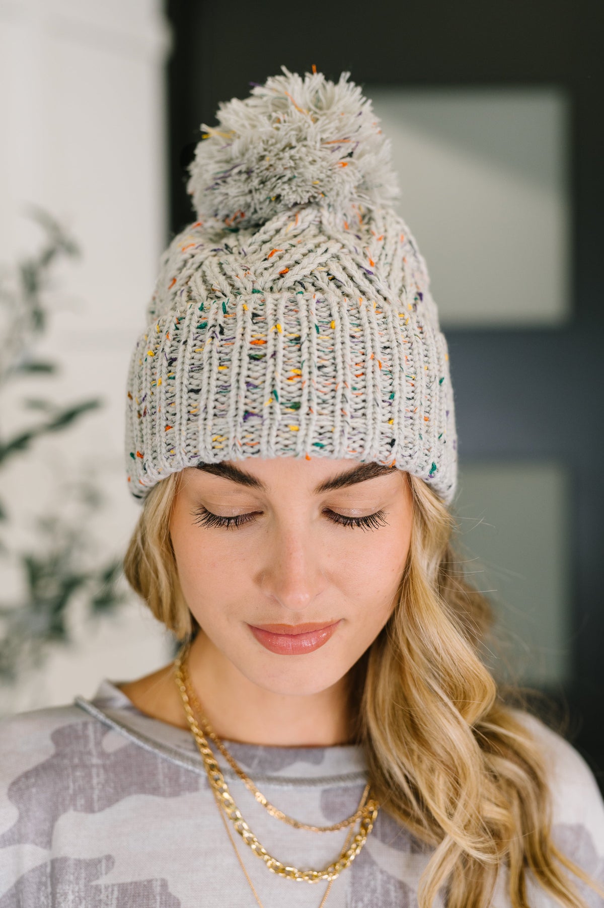 Woman wearing a knitted beanie with a pom-pom indoors