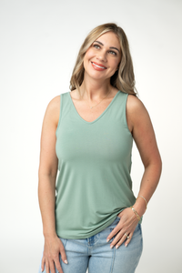 Woman wearing a light green tank top and blue jeans on a white background