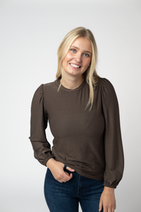 Woman wearing a brown blouse with long sleeves against a white background