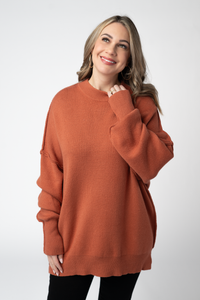 Woman wearing a rust-colored sweater against a white background