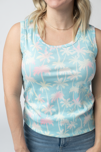 Person wearing a sleeveless top with a floral pattern on a plain background