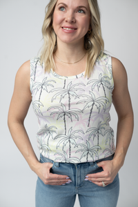 Woman wearing a sleeveless top with palm tree pattern against a plain background