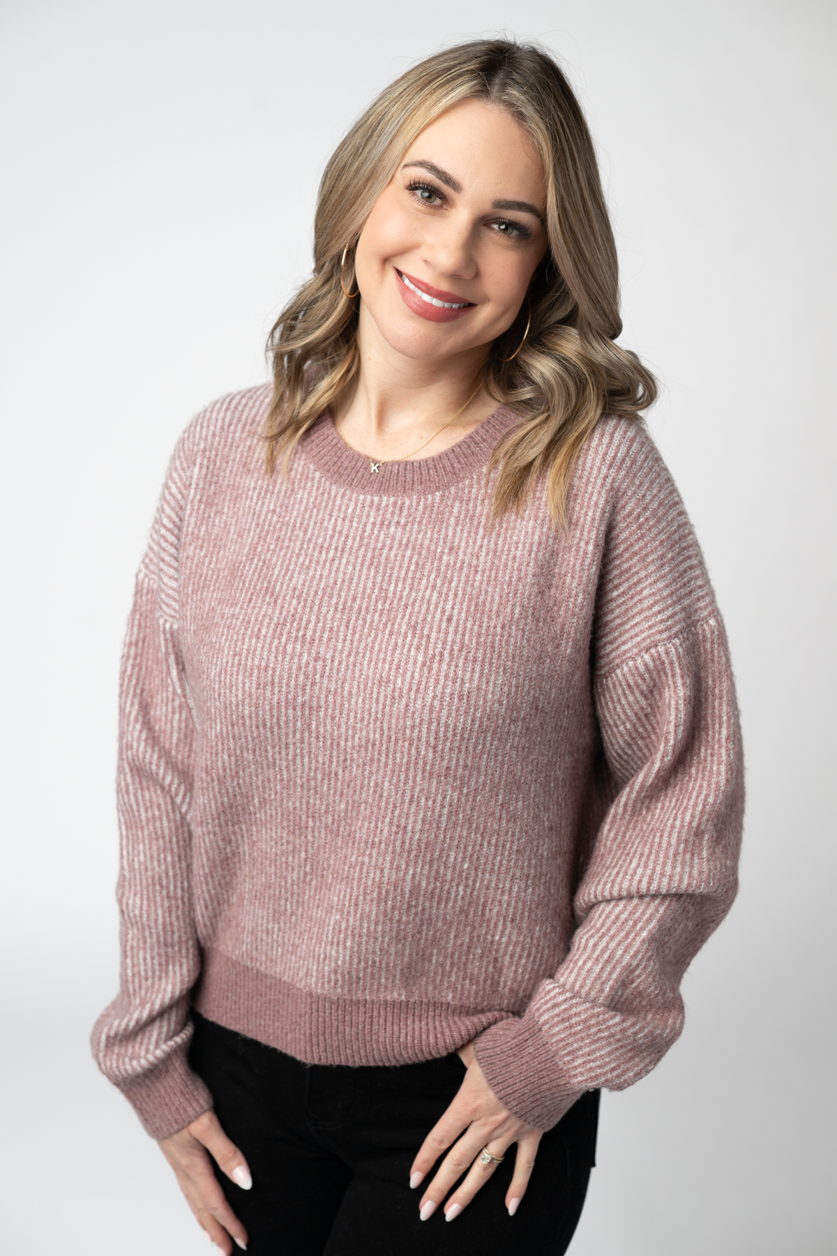 Woman wearing a pink sweater against a white background