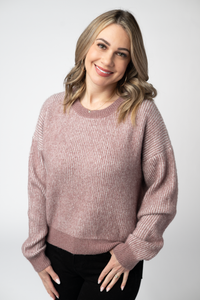 Woman wearing a pink sweater against a white background