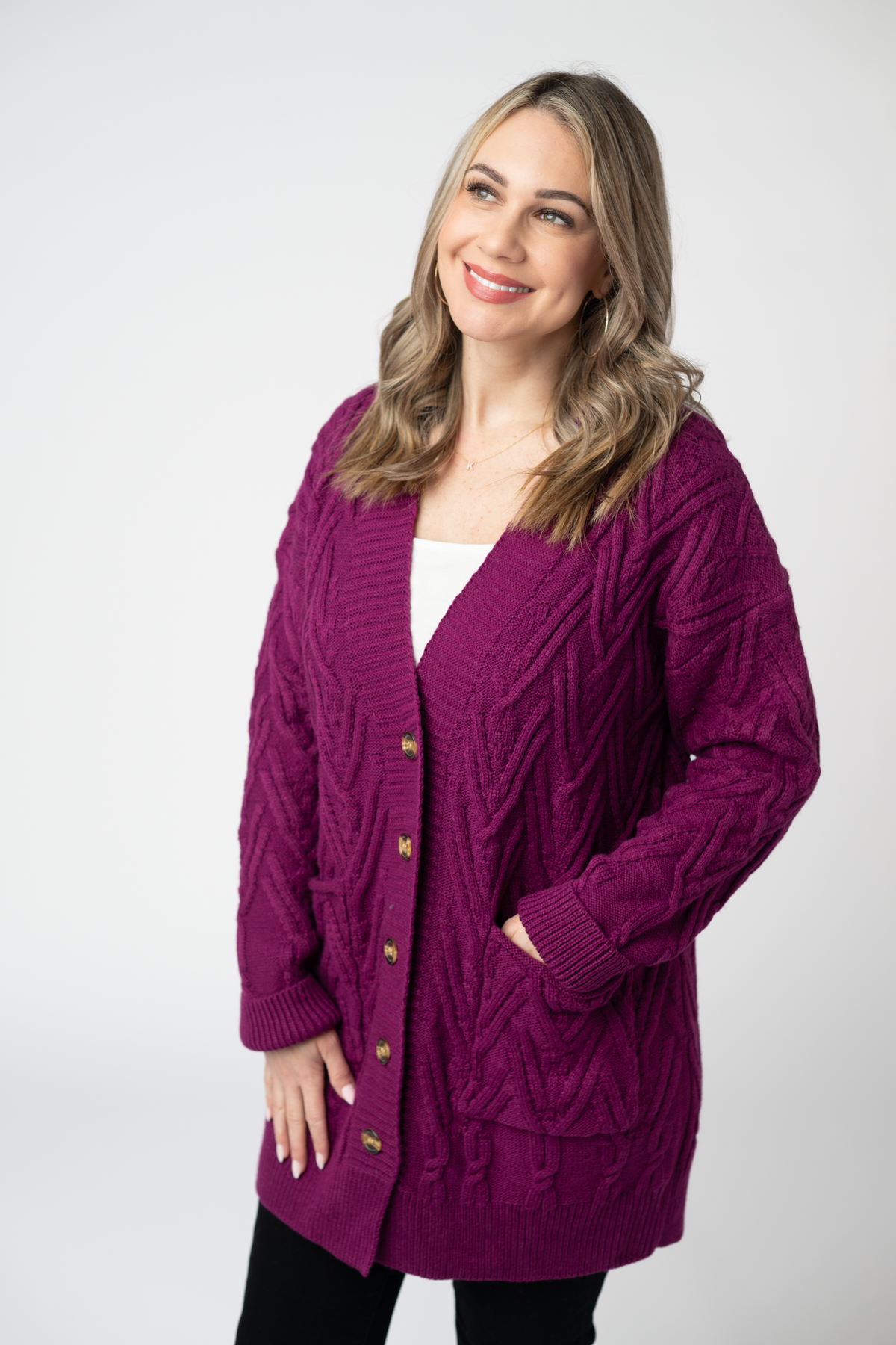 Woman wearing a purple cardigan with gold buttons on a white background