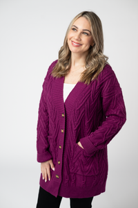 Woman wearing a purple cardigan with gold buttons on a white background