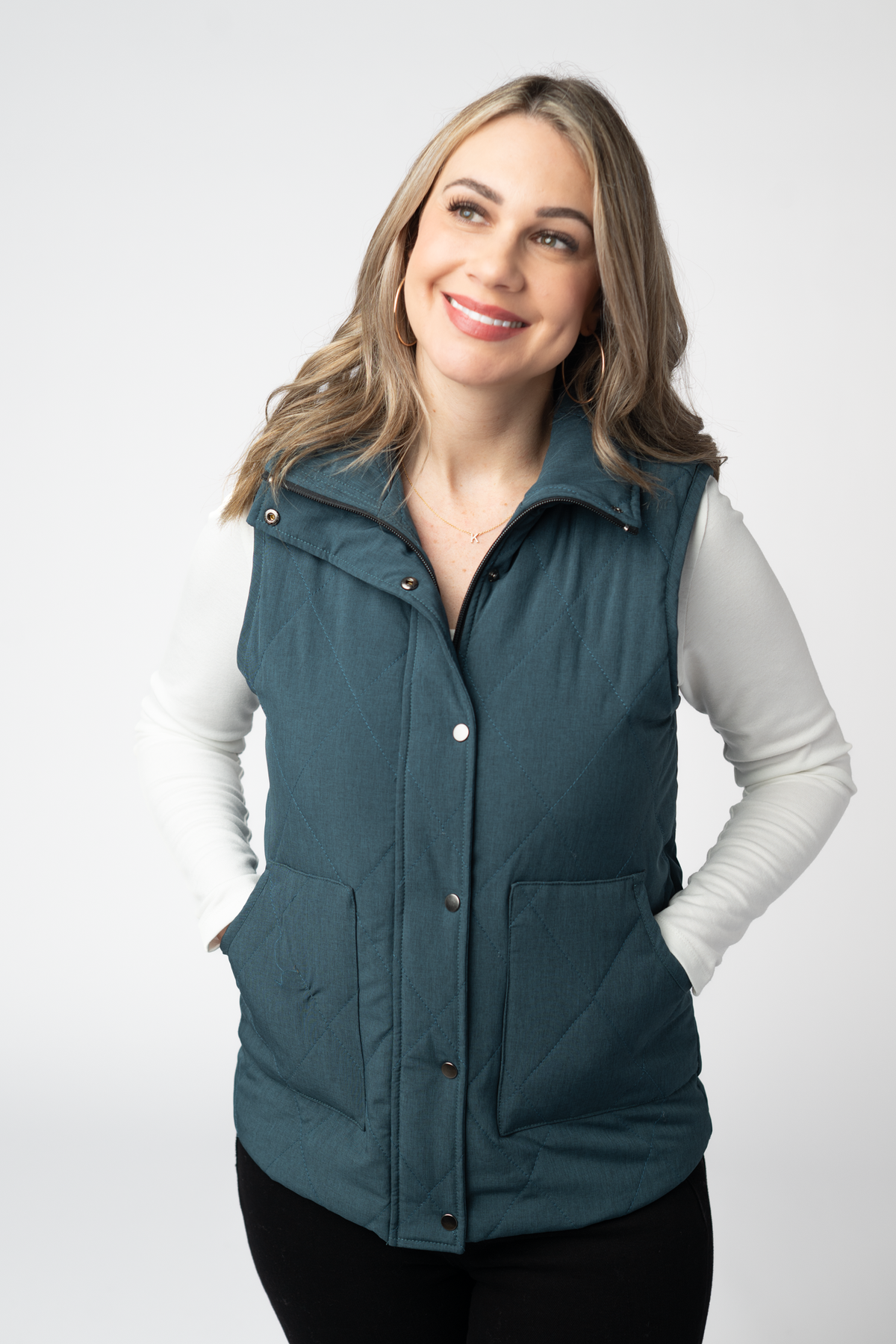 Woman wearing a teal puffer vest on a white background
