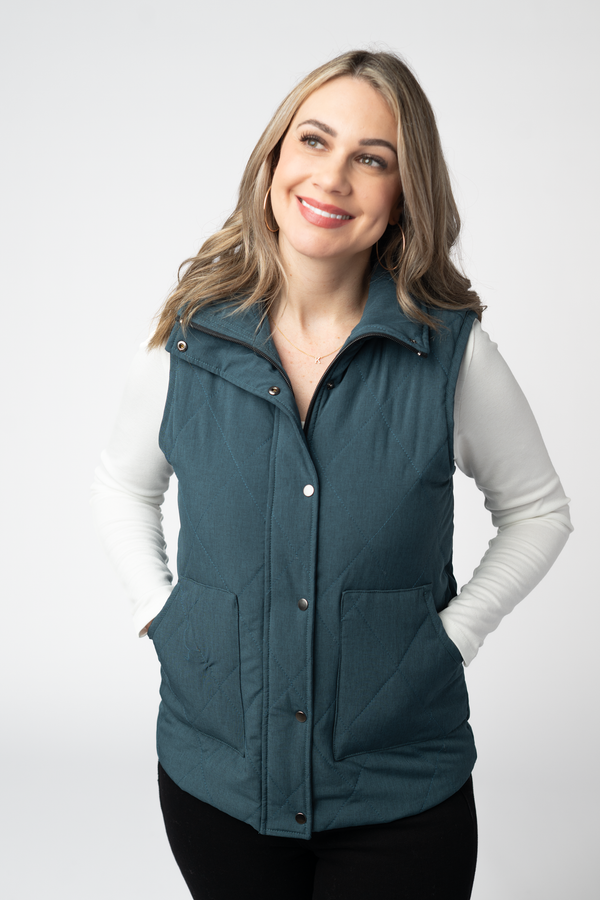 Woman wearing a teal puffer vest on a white background
