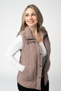 Woman wearing a quilted vest over a white long-sleeve shirt on a white background