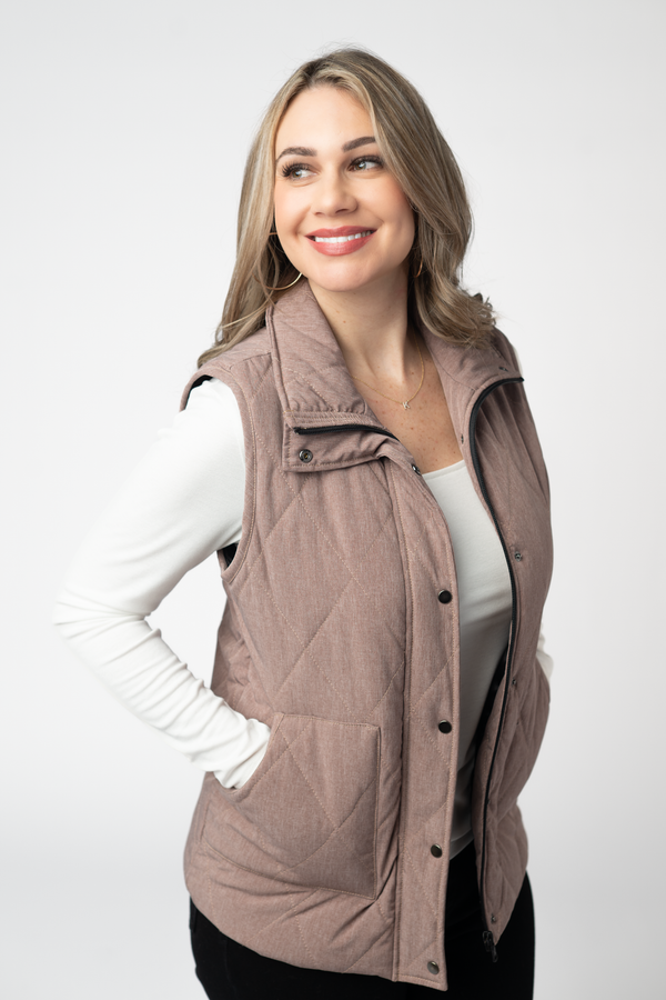Woman wearing a quilted vest over a white long-sleeve shirt on a white background