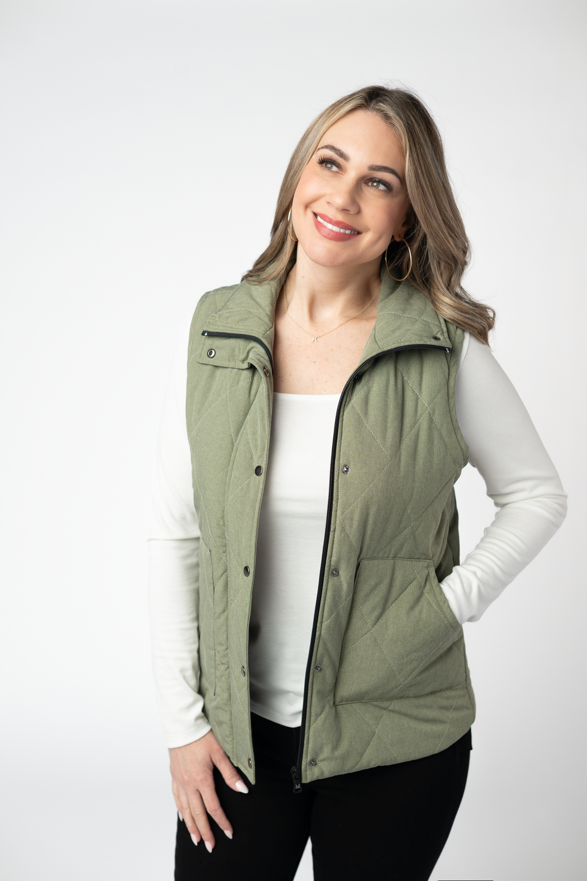 Woman wearing a green vest over a white shirt on a white background