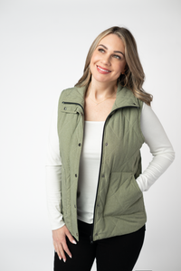 Woman wearing a green vest over a white shirt on a white background
